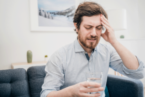 a person holds their head in pain as they realize the links between alcohol and the brain