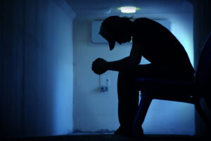 a person sits sadly in a dim hallway wondering 'does forming a drug tolerance mean im addicted?"