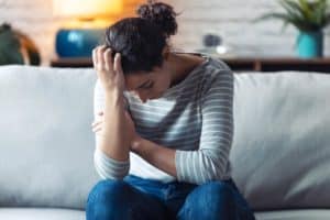 a woman sits on a couch holding her head