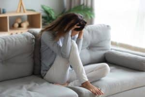 a distraught woman sits on the floor with her head in her hands