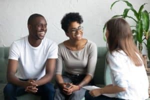 a couple sits on a couch talking to a family counselor