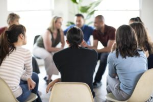 people sit in a circle discussing the benefits of group counseling