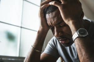 a person holds their head after experiencing the dangerous effects of mixing alcohol and cocaine