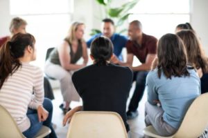 a circle of people sit and talk during group counseling