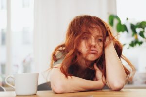 a disheveled person sits at a table possibly struggling with heroin withdrawal symptoms