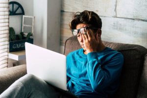 a person rubs their face while sitting at a computer possibly struggling with symptoms of valium abuse