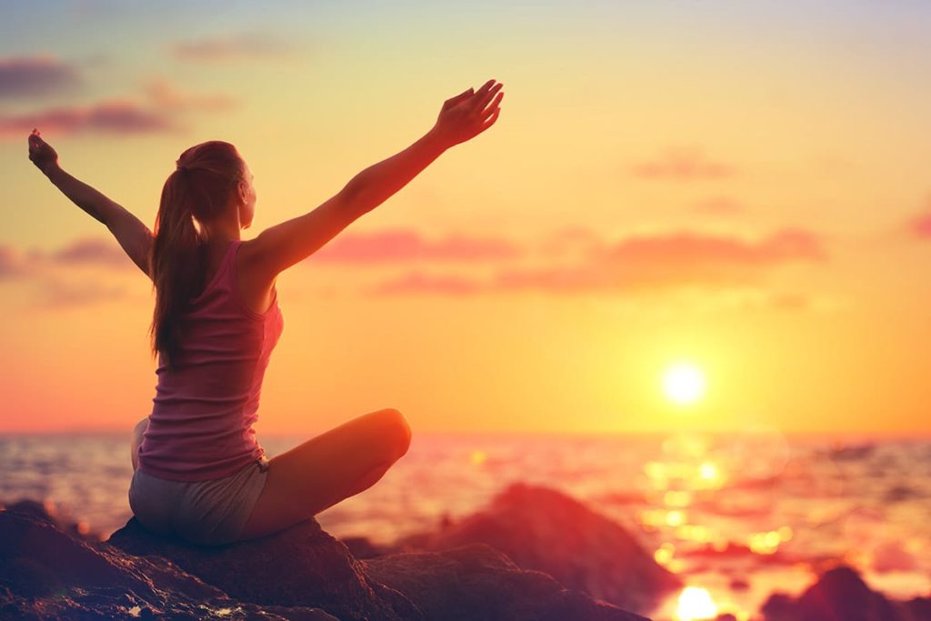 a person sits near the ocean being outside is a great step to quit drinking