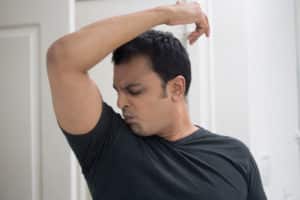 a person smells their armpit for Body odor alcohol