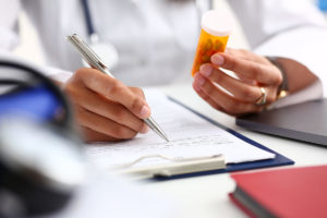 a doctor fills a prescription for Medication assisted treatment