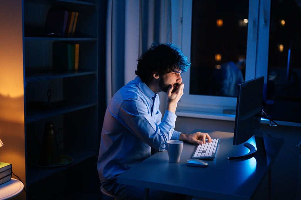 a person sits in the dark in front of a computer glow, learning about the differences between crack vs cocaine