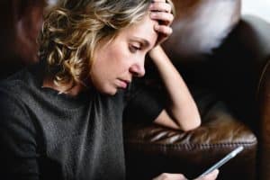 a person leans against a couch while looking up information on addiction and the brain