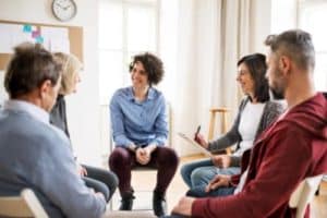 a group of people sit in a circle in chairs and talk about their crack addiction treatment