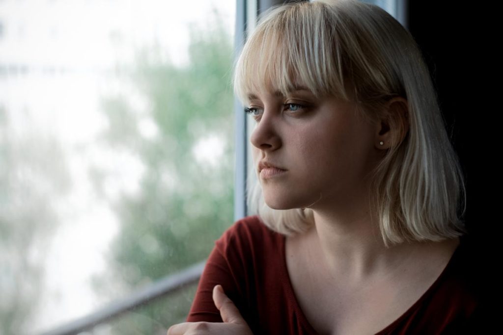 a person looks sadly out a window while understanding psychological dependence
