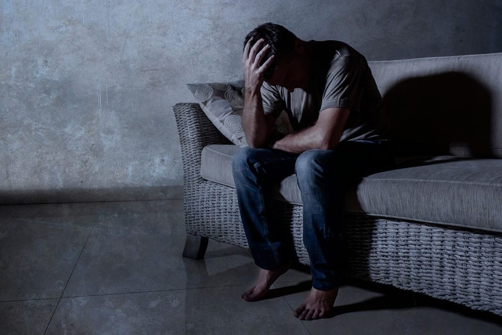 a person sadly sitting on the edge of a bed realizing the dangers of crack cocaine