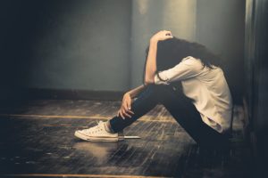 a person struggling with hydroxyzine abuse sits on the floor in anguish