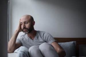 a person struggling with percocet abuse looks out of a window while sitting on a couch