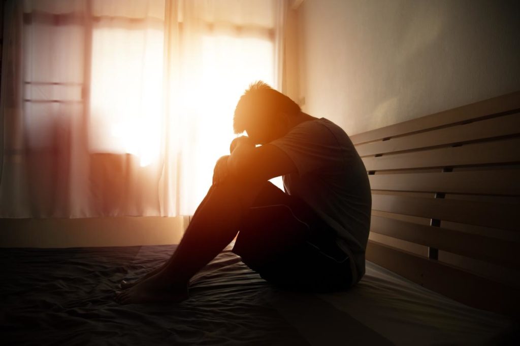 a person struggling with ecstasy abuse sits in a dark hallway at sunset