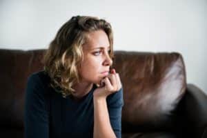 a person pondering how a process addiction works sits on a couch