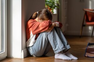 a person struggling with Adderall Abuse sits on a floor with their head on their knees