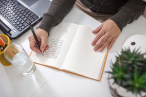 a person writes managing stress and anxiety in their journal