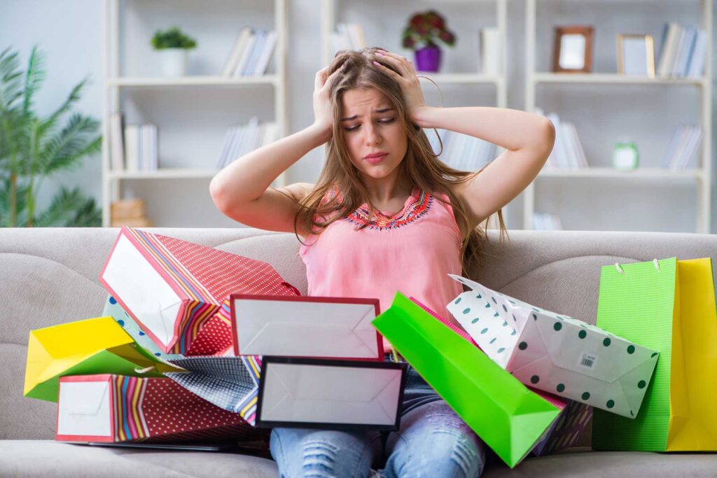 a person looks overwhelmed with a lot of bags on their lap as they wonder how to stop a shopping addiction