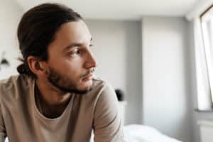 a person with high-functioning depression looks out of a window from bed