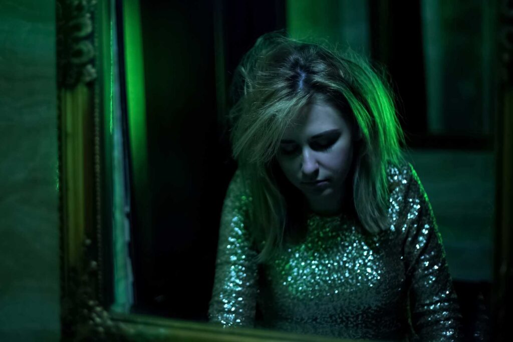 a person in a roomm with a green light ponders how long does ecstasy stay in your system