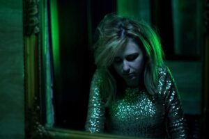 a person in a roomm with a green light ponders how long does ecstasy stay in your system