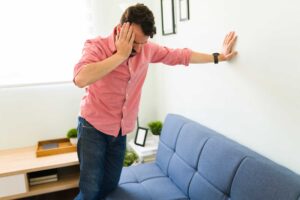 a person steadies themselves on a wall while holding their head struggling with robaxin abuse