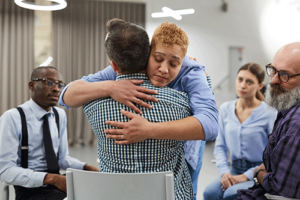 two people hug in a group in an alcohol detox center