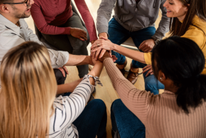 a group puts their hands toward the middle of a circle in a heroin detox center