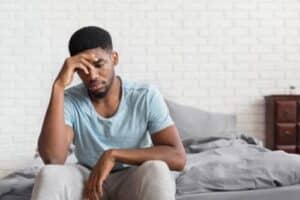 a person holds their head at the edge of a bed realizing they need Ecstasy Abuse Rehab