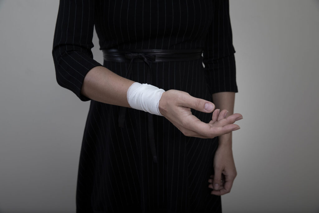 a person holds out a bandaged wrist, possibly before researching what is self-harm