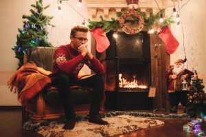 a person sits near a fireplace and holiday decorations as they calmly try to remember tips for holiday stress