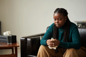 a person dealing with early signs of dual diagnosis sits on a couch in therapy