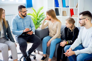 a therapist addresses a family in a family therapy program